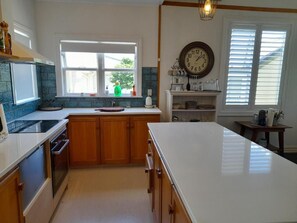 A kitchen with wooden cabinets, a white countertop, a built-in oven, and a window with blinds. - Old-World Villa Charm in the Heart of Featherston • 2 Beds • Walk to Town (Featherston)