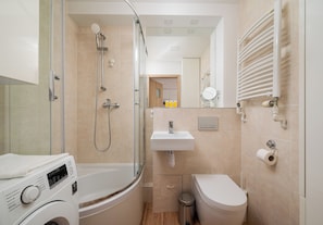 Une salle de bain moderne avec une douche à parois de verre, un lavabo intégré, des toilettes et un lave-linge.