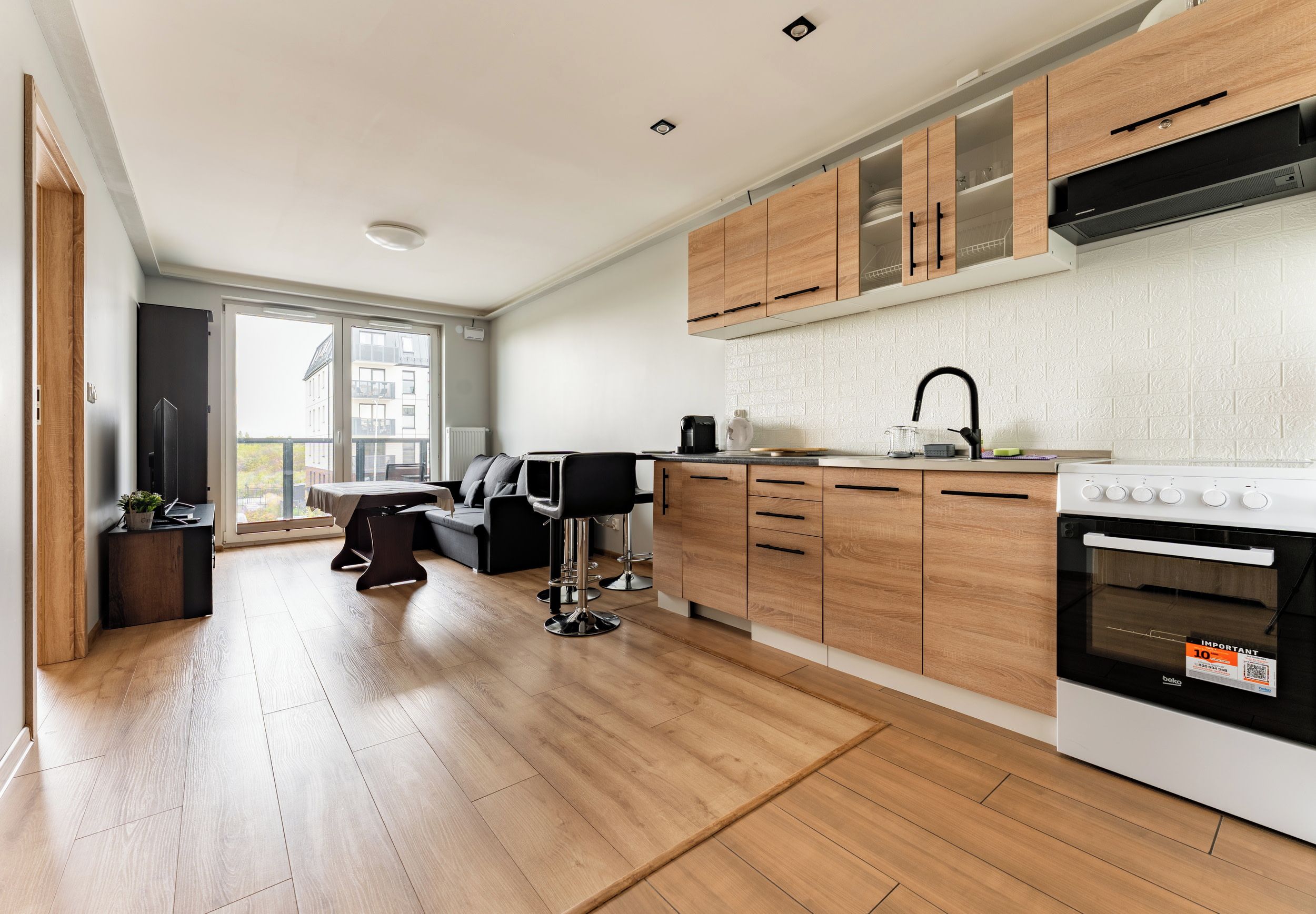 Eine moderne Küche mit Holzausbau, einem eingebauten Backofen und einem Essbereich mit einem schwarzen Stuhl und Tisch.