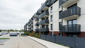 Een modern appartementencomplex met balkons en een verharde oprit.