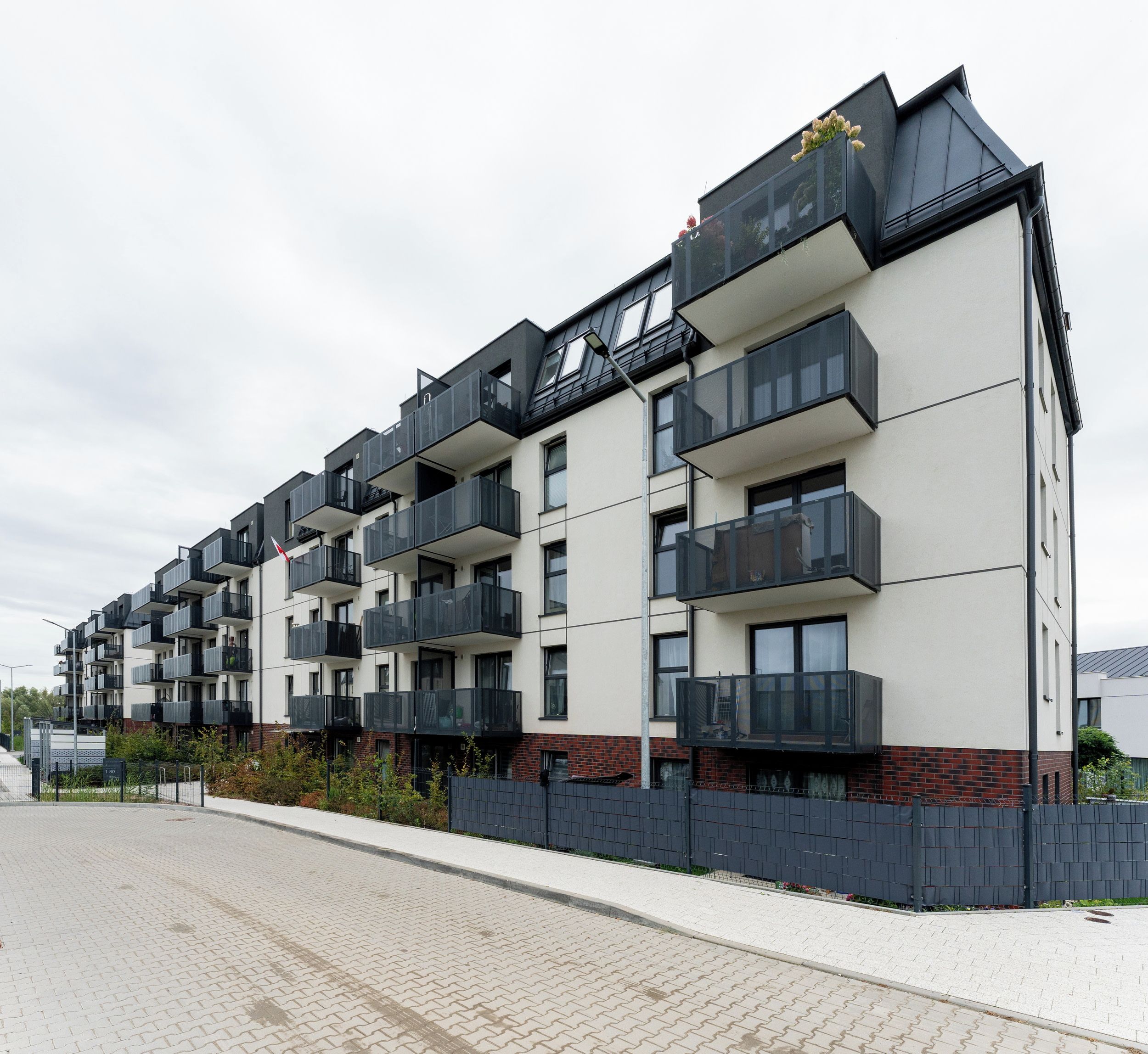 Un edificio residencial de varios pisos con balcones, techo plano y base de ladrillo.