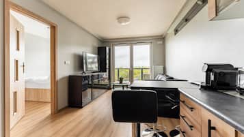 A modern kitchen with a dining area, a bar stool, and a television.
