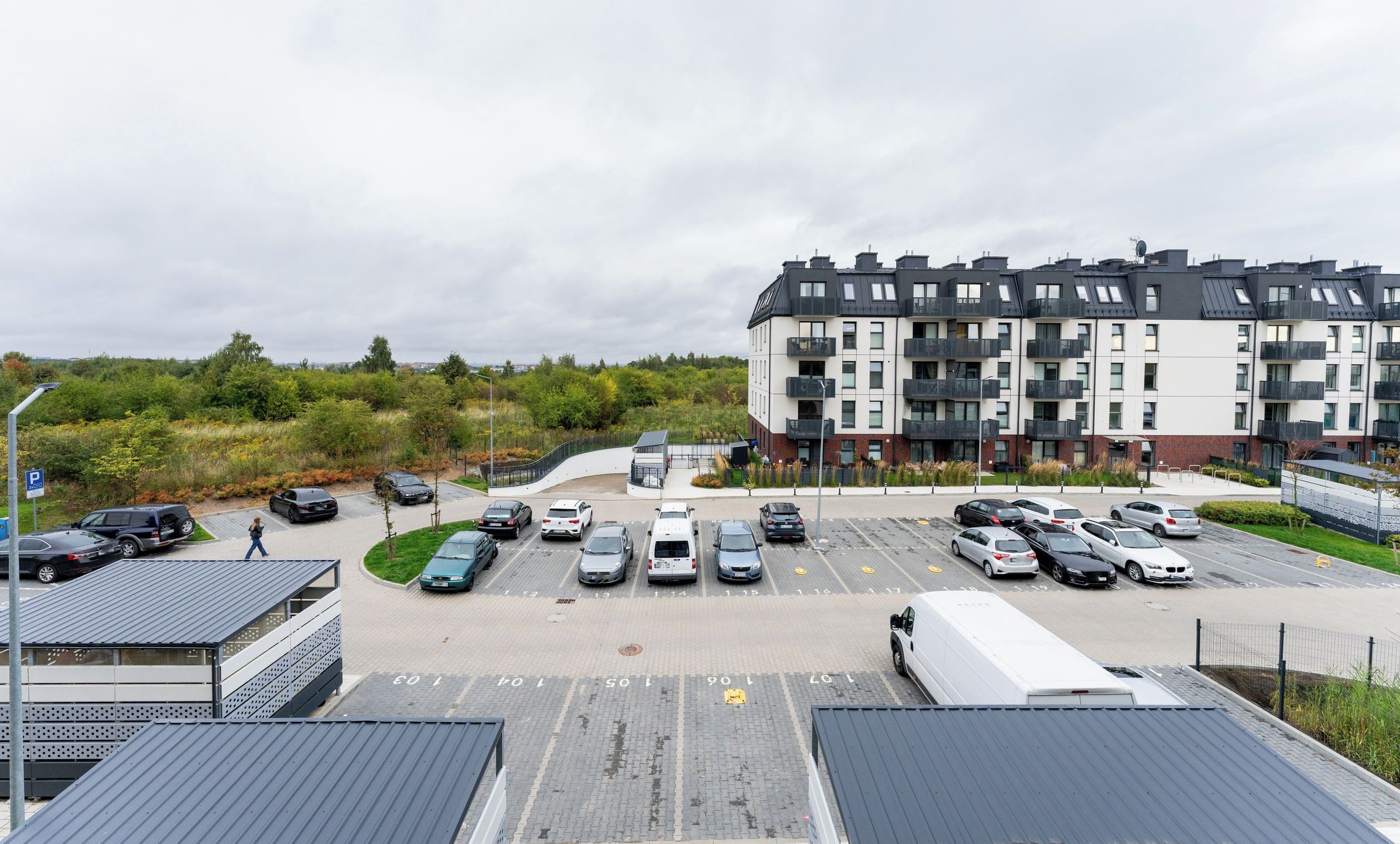 A multi-story residential building with a parking lot in front.