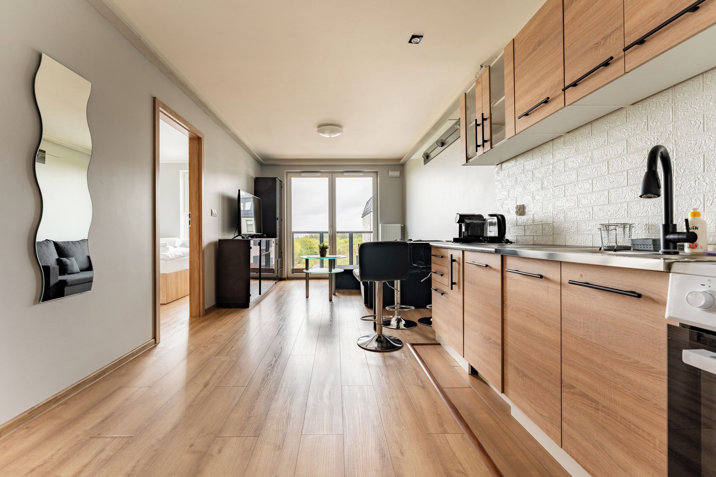 A modern kitchen with wooden cabinets, a black faucet, and a glass-top table with bar stools.
