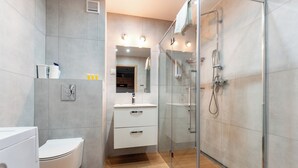 Een moderne badkamer met toilet, wastafel en douche.
