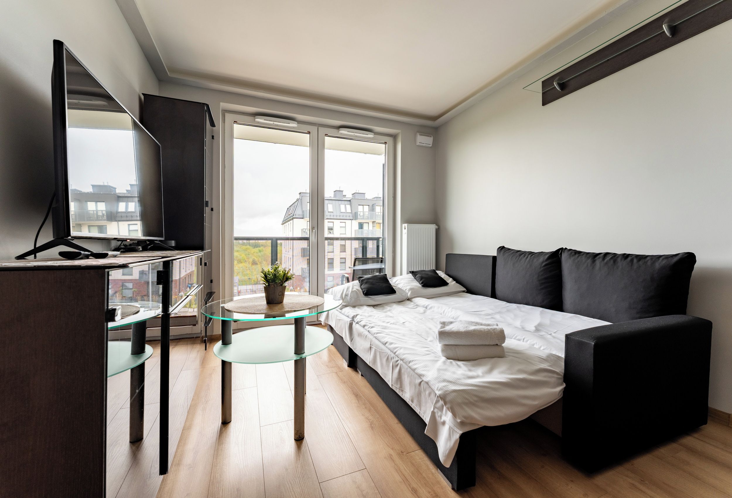 Une chambre moderne avec un lit, un bureau et un balcon.