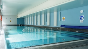 Ein hallenbad mit deutlich abgegrenzten Bahnen, Sicherheitshinweisen und einer Uhr an der Wand.