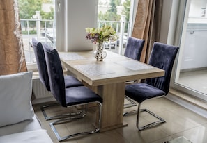 Uma área de jantar com mesa, cadeiras, um vaso de flores e vista pela janela.