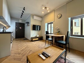 Ein moderner Wohnraum mit Küche, Essbereich und einem an der Wand befestigten Fernseher.