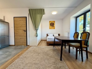 A room with a bed, a table with chairs, a radiator, and a window with a view. - Wrocław Airport Standard Studio (Wrocław)