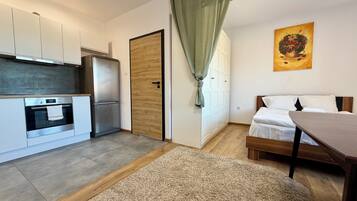 Eine moderne Küche mit Einbauofen und Kühlschrank, einer Holztür sowie einem Essbereich mit Tisch und Stühlen.