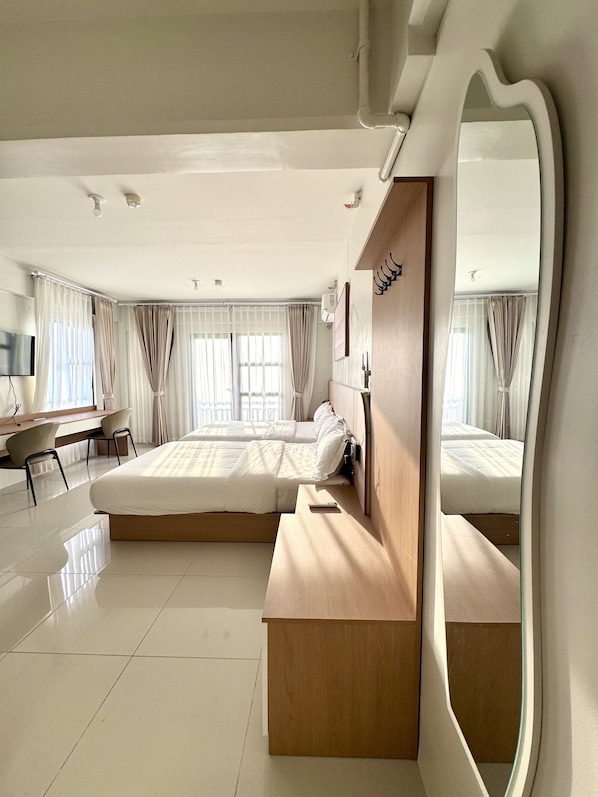 A modern hotel room with a large bed, a wooden bench, a desk, and a mirror. - Royal Oceancrest Panglao 1 (Dauis)