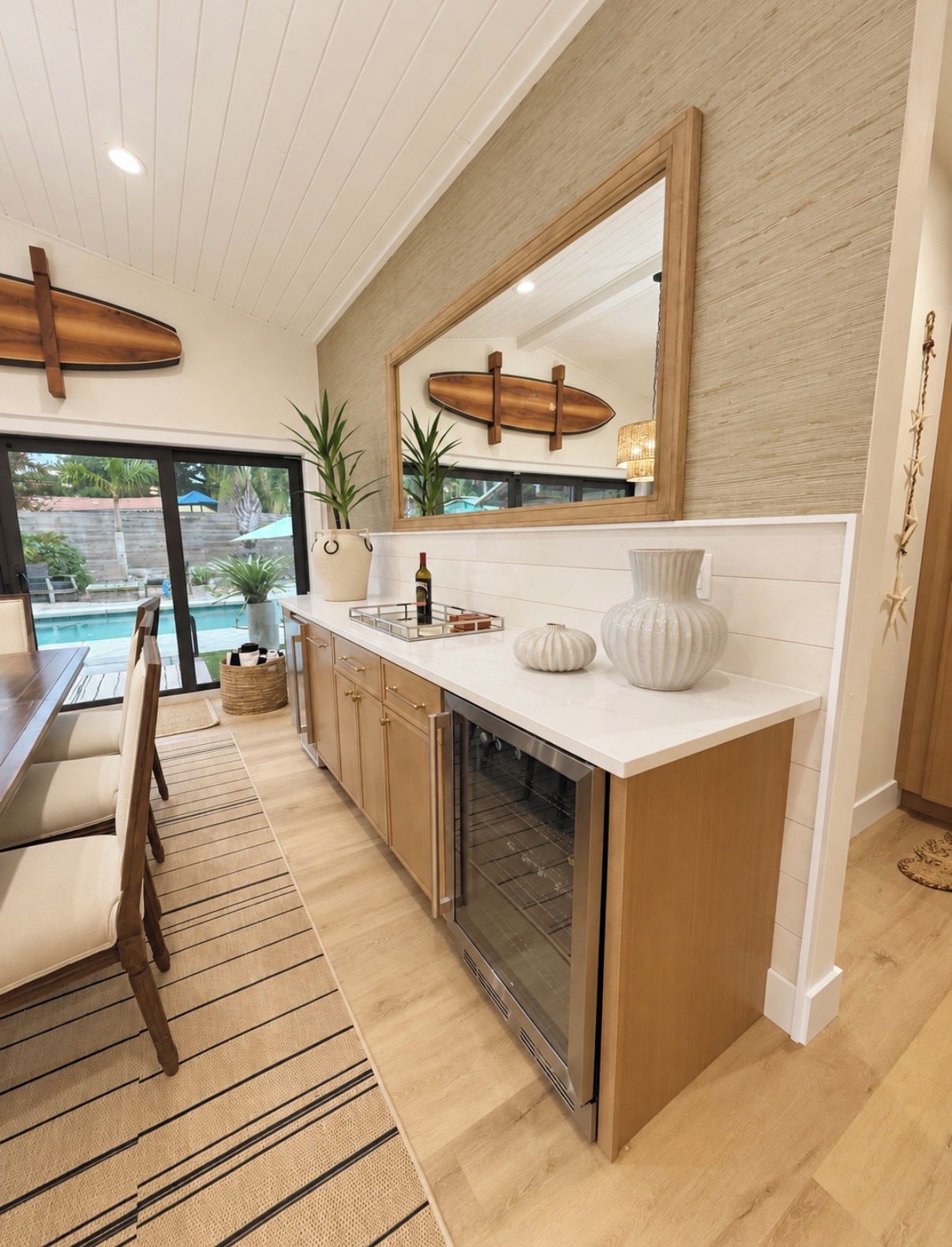 A modern kitchen with a large island, wooden cabinets, and a view of a pool.
