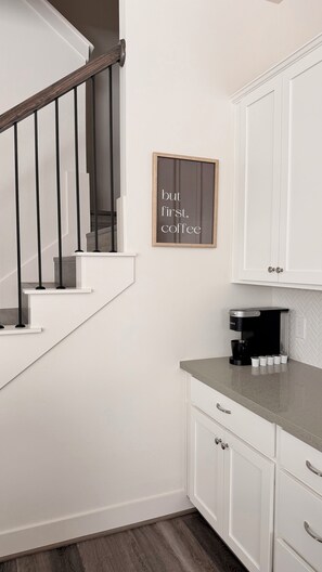 A modern kitchen with white cabinetry, a coffee maker, and a framed sign on the wall. - Modern Cozy Retreat Minutes From Downtown Houston (Houston)