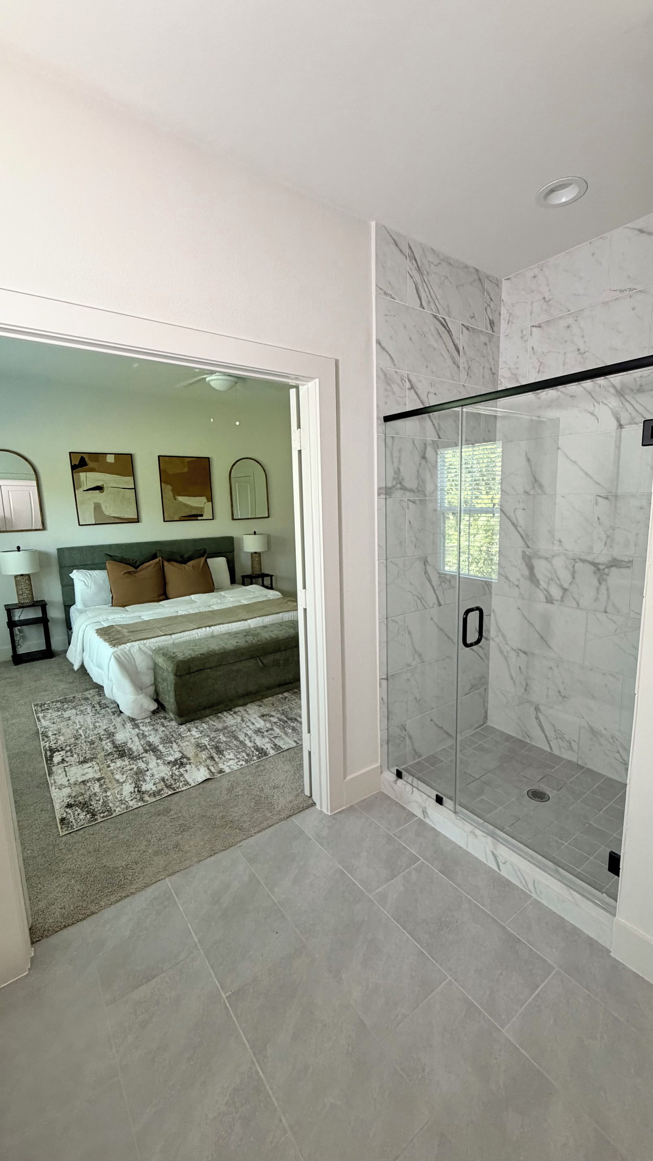 Une salle de bain moderne avec une douche à parois de verre, des carreaux de marbre et des toilettes apparentes.