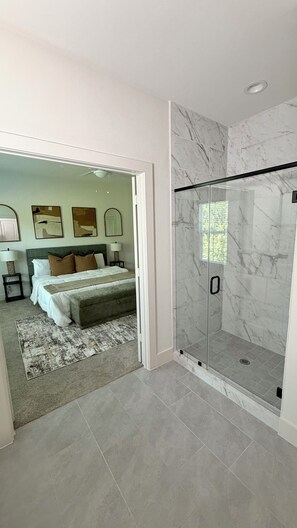 Een moderne badkamer met een douchecabine van glas, marmeren tegels en een zichtbaar toilet.