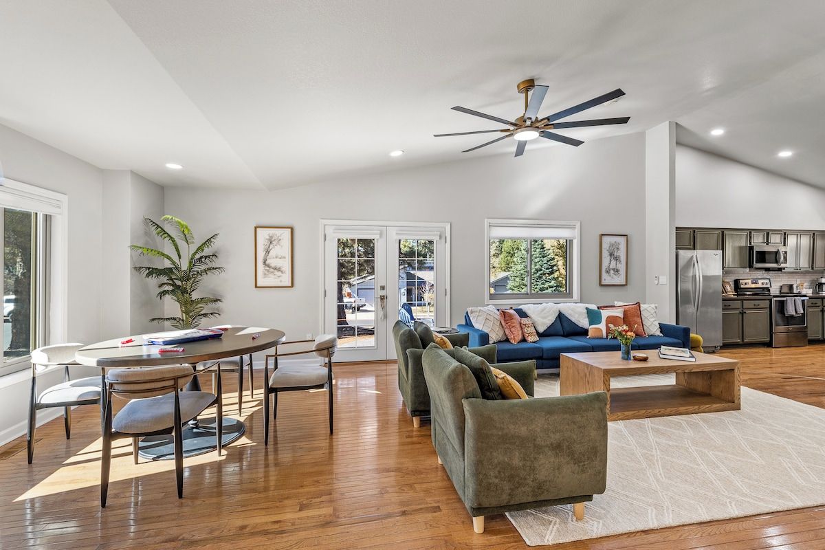 A spacious living area with a dining table, sofas, and a kitchen in the background.