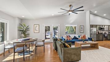 A spacious living area with a dining table, sofas, and a kitchen in the background.