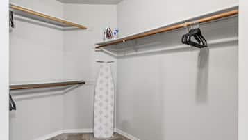 Een inloopkast met houten kledingroedes, een hangstang en een douchegordijn.