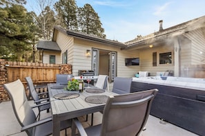 An outdoor patio with a dining table, chairs, and a hot tub. - Country Club Home 3BR, Golf, Hot Tub & Pines (Flagstaff)
