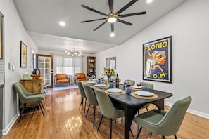 Un comedor con una mesa de madera oscura dispuesta para cuatro personas, rodeada de sillas tapizadas en verde.