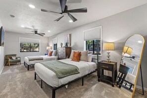 A bedroom with two beds, a ceiling fan, a dresser, a nightstand, and a mirror. - Country Club Home 3BR, Golf, Hot Tub & Pines (Flagstaff)