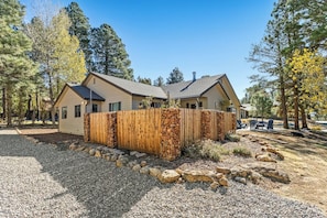 A single-story house with a fenced yard, surrounded by trees. - Country Club Home 3BR, Golf, Hot Tub & Pines (Flagstaff)