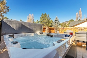 A hot tub area with a stone wall backdrop and a wooden fence. - Country Club Home 3BR, Golf, Hot Tub & Pines (Flagstaff)