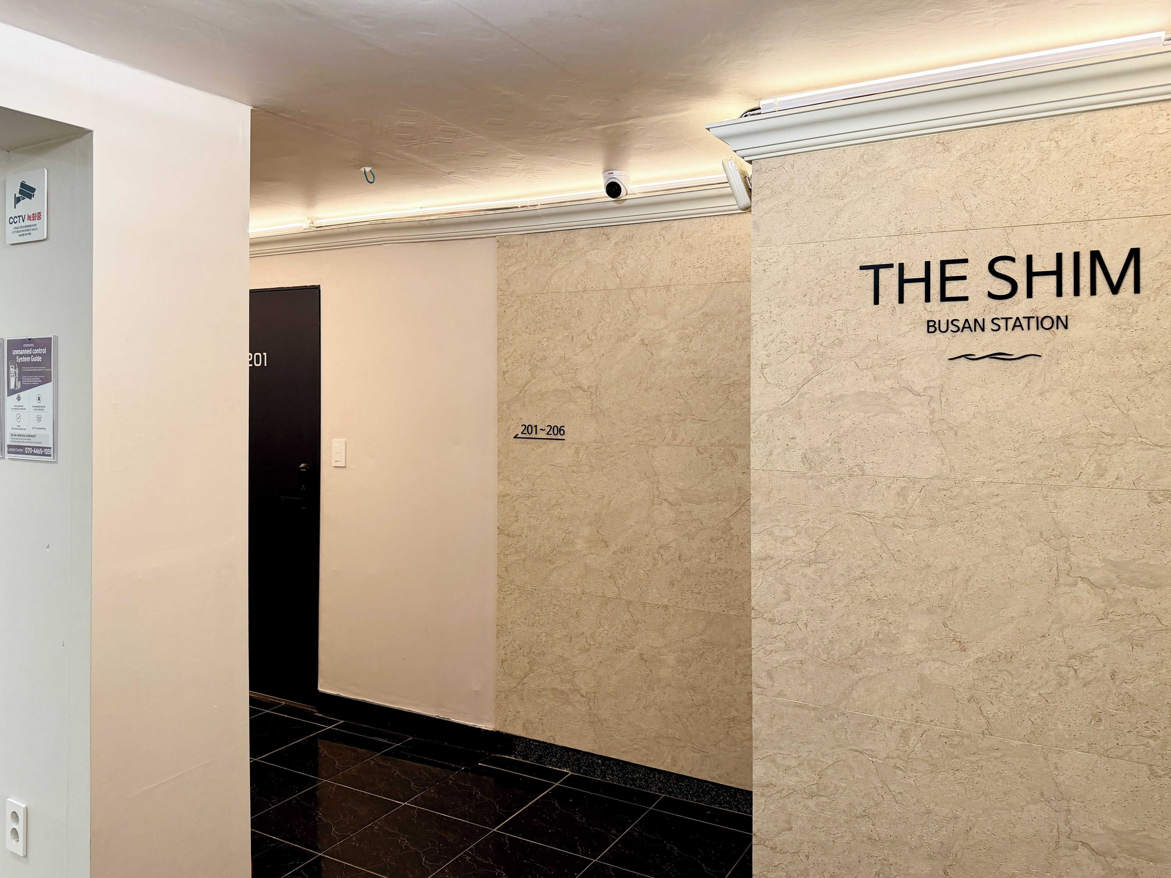 A hallway with a sign for 'THE SHIM BUSAN STATION' and numbered doors.