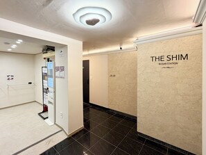Un pasillo con piso de baldosas negras, una puerta con el rótulo '201-206' y una pared con la señalización 'THE SHIM BUSAN STATION'.