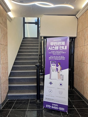 Una escalera con un cartel informativo morado y un número de contacto.