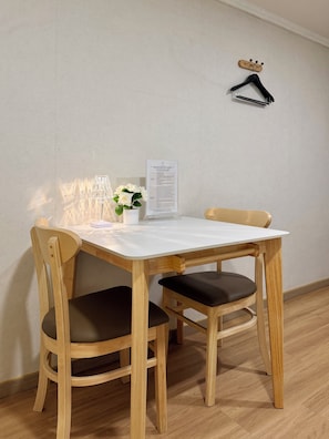 Una mesa de madera con dos sillas, una planta pequeña en maceta y un cartel en la pared.