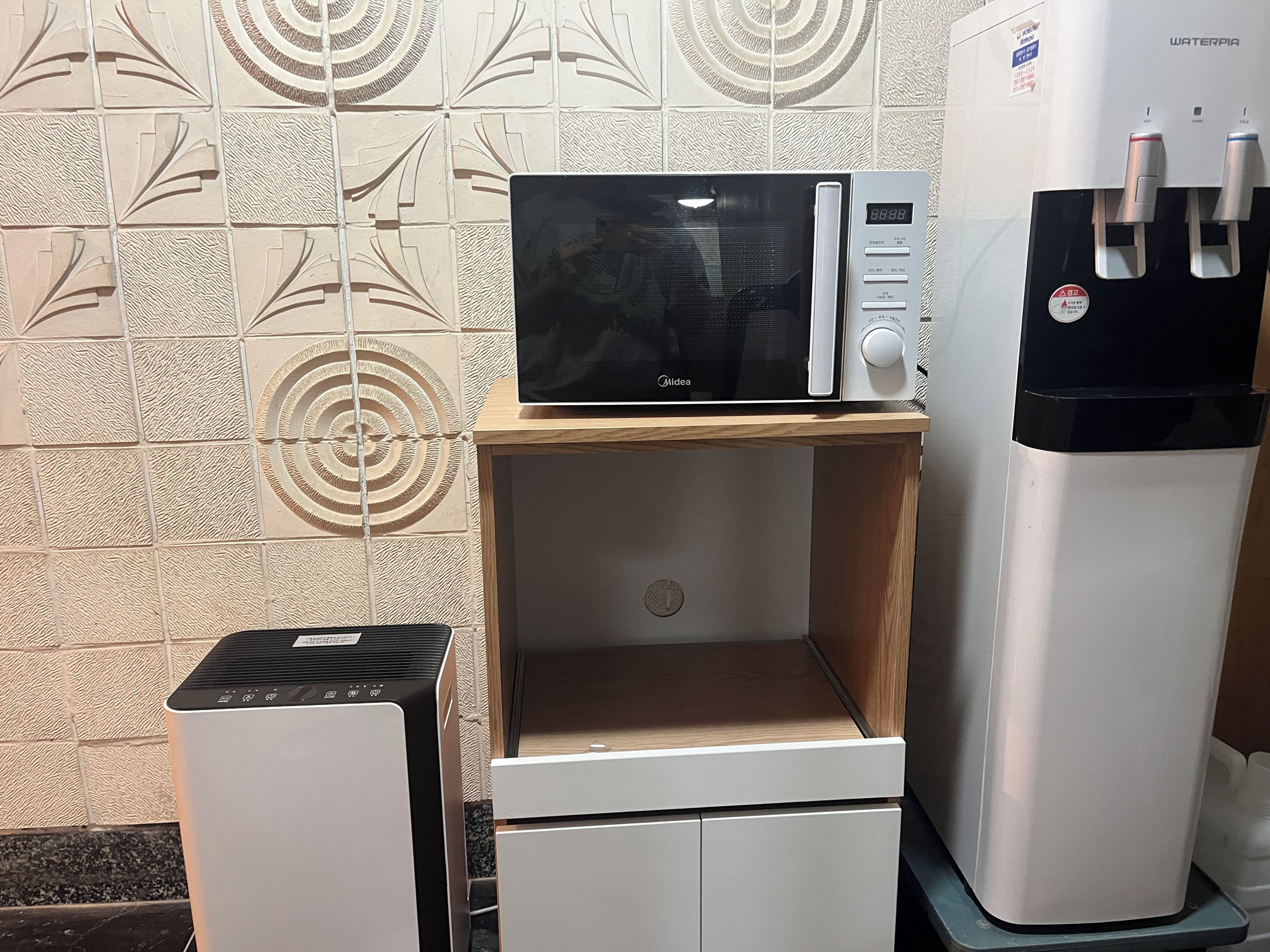 Una kitchenette equipada con microondas, dispensador de agua y un refrigerador pequeño.