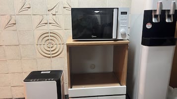 Una kitchenette equipada con microondas, dispensador de agua y un refrigerador pequeño.
