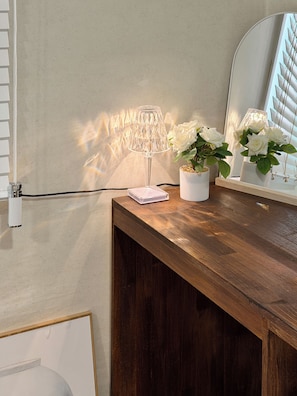 A wooden vanity with a mirror, a clear lamp, and white flowers. - The Shim Hotel Busan Station (Busan)