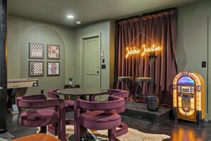 A room with a table and purple chairs, a jukebox, and a neon sign. - Juniper & Jukebox - Movie Room, Rooftop w/ Mural & Fire Pit, 5 Bedrooms, 9 bed (Nashville)