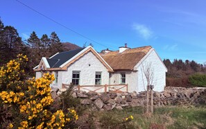 Ein Haus mit Naturstein-Fundament, einem Strohdach und einer weißen Fassade.