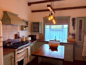 A kitchen with a stove, oven, and wooden countertop. - Gorse Cottage Connemara | Wild Atlantic Way | Sleeps 4 | Pet Friendly (Cashel)