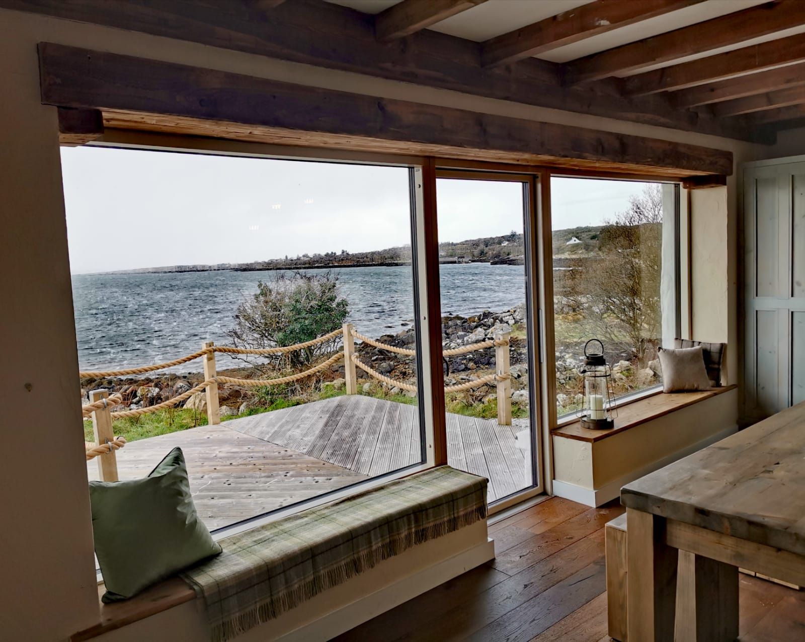 A room with a large sliding glass door leading to a wooden deck overlooking a body of water.