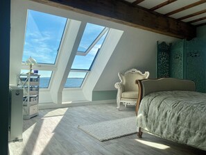 Un dormitorio con tragaluz, una cama, una silla y un panel decorativo en la pared.