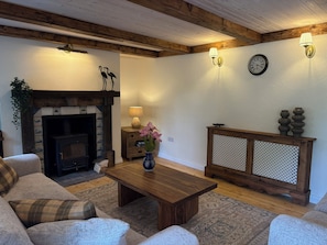 A cozy living room with a fireplace, wooden furniture, and decorative items. - Mayfly Cottage in Oughterard | Wild Atlantic Way | Sleeps 6 | Pet Friendly (Cashel)