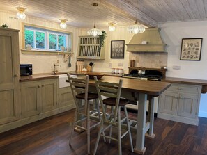 Une cuisine avec des meubles en bois, un îlot central et des luminaires suspendus.