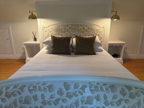 A bed with a white headboard and two nightstands with lamps, a floral-patterned bedspread, and a wooden floor. - Mayfly Cottage in Oughterard | Wild Atlantic Way | Sleeps 6 | Pet Friendly (Cashel)