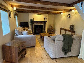 A cozy living room with a fireplace, wooden beams, and a television. - Mayfly Cottage in Oughterard | Wild Atlantic Way | Sleeps 6 | Pet Friendly (Cashel)