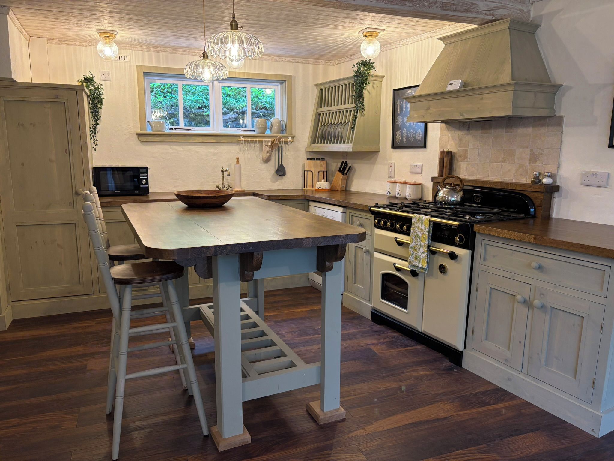 A kitchen with a wooden table, bar stools, a stove, and a window with plants.
