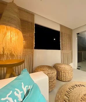 Een modern interieur met een groot raam, geweven zitzakken en een hanglamp.