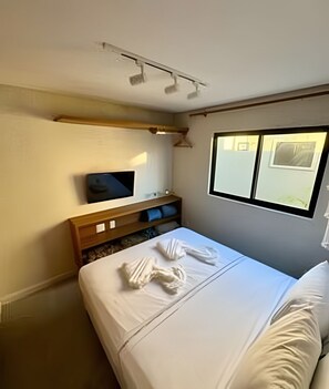Ein Hotelzimmer mit Bett, Fernseher, Fenster und einem Holzboden.