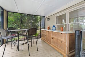 A covered outdoor dining area with a table and chairs, a wooden cabinet with a window, and a tall air purifier. - Hillview Lakefront Retreat w/ Private Pier (Lexington)