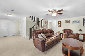 A spacious living room with a brown leather sofa, a wooden coffee table, and a ceiling fan. - Hillview Lakefront Retreat w/ Private Pier (Lexington)