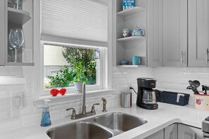 A modern kitchen with a double sink, a coffee maker, and a window with a view of greenery. - Hillview Lakefront Retreat w/ Private Pier (Lexington)